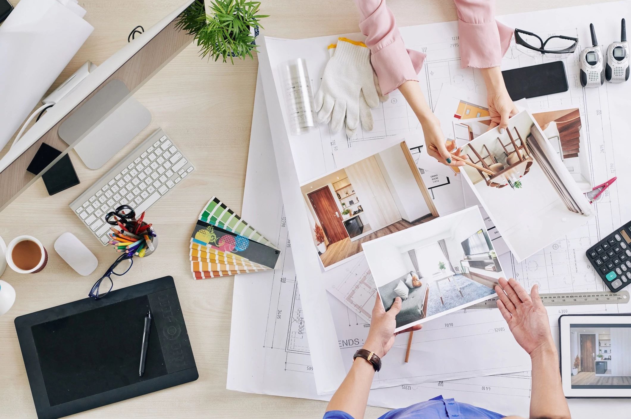 two pair of hands working on a desk with plans and documents - bdflooringinc