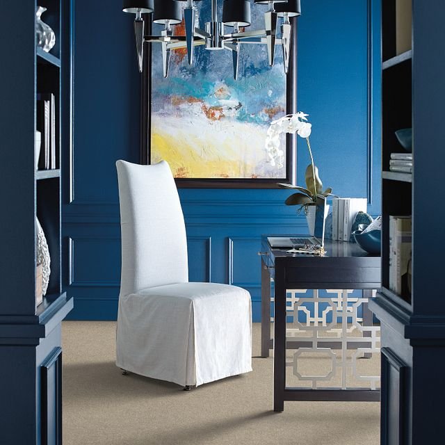 white covered chair in room with blue walls and colorful painting - B D Flooring Inc